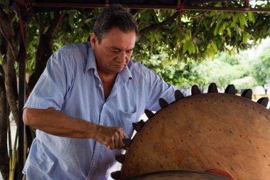 Elderly Latino man at work with a wood mill in Neiva - Huila - Colombia clipart