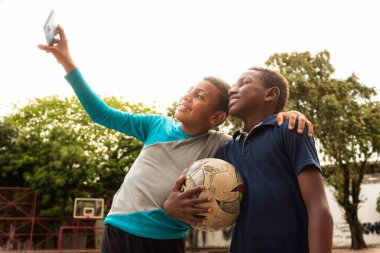 Neiva-Huila-Kolombiya parkında akıllı telefonlu iki siyah Latin çocuğun selfie 'si.