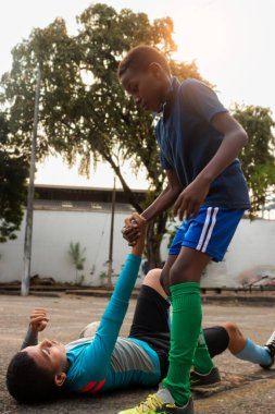 Black Latino boy helping to lift a Hispanic boy off the ground in a park in Neiva - Huila - Colombia clipart