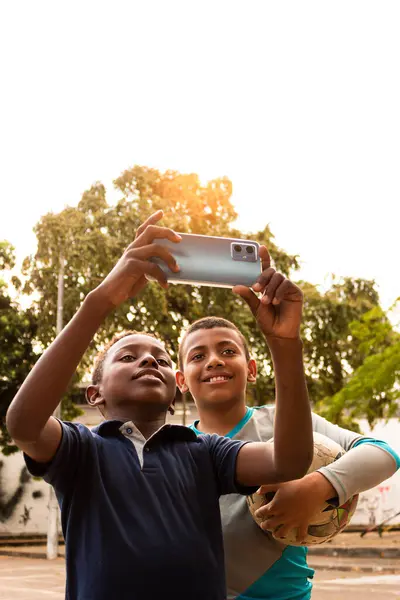 Neiva-Huila-Kolombiya parkında ellerinde topla selfie çeken mutlu Latin çocuklar.