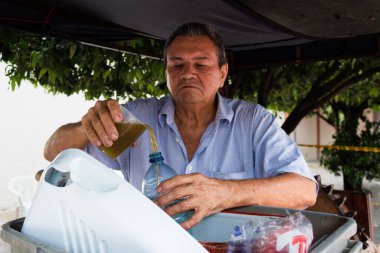 Yaşlı Latin adam Guarapo 'ya plastik şişeyle servis yapıyor.