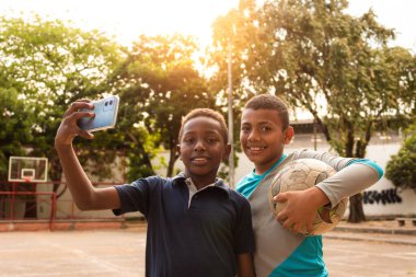 Siyah Latin çocuklar Neiva-Huila-Kolombiya parkında cep telefonuyla selfie çekiyorlar.