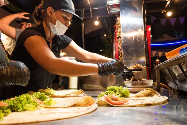 Genç Latin bir kadın Neiva-Huila-Kolombiya 'daki bir restoranda domuz ve biftekle burrito hazırlıyor.