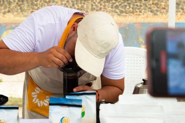 Unrecognizable Latino man tasting a coffee drink at an event in Neiva - Huila - Colombia clipart