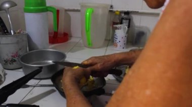 Latin bir büyükannenin Neiva-Huila-Kolombiya 'daki evinin mutfağında bıçakla patates derisini kestiği an. Kolombiya yemeği ve ev hanımı kavramı