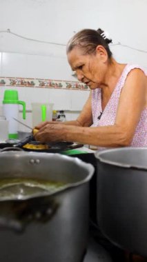 Latin bir büyükannenin Neiva Huila Kolombiya 'daki evinde bir mutfakta bıçakla patates derisini kestiği an. Kolombiya yemeği ve ev hanımı kavramı