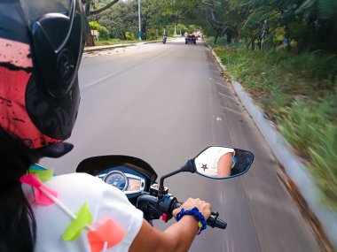 Brunette Latina woman driving a motorbike on a road in Neiva - Huila - Colombia. Travel concept; tourism and transportation clipart