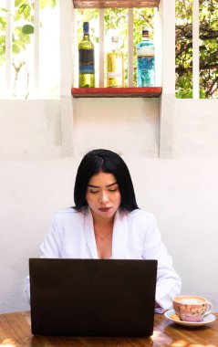 Young latina woman working on a laptop in a coffee shop in Neiva - Huila - Colombia. Businesswoman concept  clipart