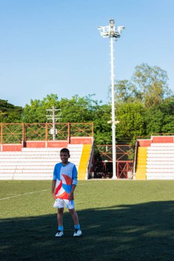 Portrait of a Colombian soccer player boy in blue uniform smiling in a stadium in Neiva - Huila - Colombia. Sports concept clipart