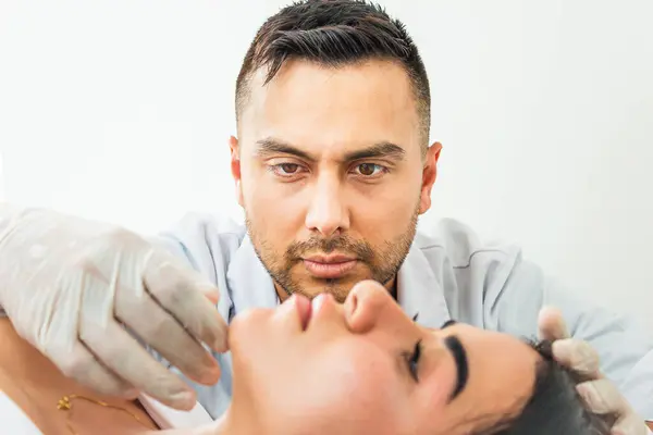 Kolombiyalı genç bir doktorun portresi, Neiva, Kolombiya 'da bir klinikteki danışma odasında Latin bir kadın hastanın yüzünü inceliyor. Sağlık ve güzellik kavramı