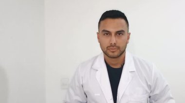 Kolombiyalı beyaz önlüklü bir doktor Neiva-Huila-Kolombiya 'daki bir kliniğin koridorunda yürürken kameraya bakıyor. Sağlık, iş ve ilaç kavramı
