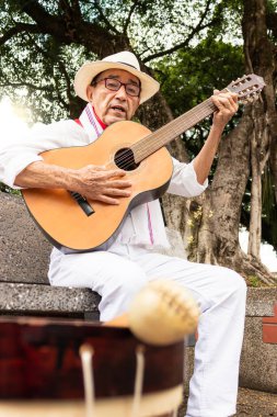 Beyaz şapkalı yaşlı Kolombiyalı adam Yaguara 'da halka açık bir parkta, Huila-Kolombiya' da davul çalarken oturuyordu. Yaşam tarzı, Kolombiya kültürü ve yaşlılar konsepti