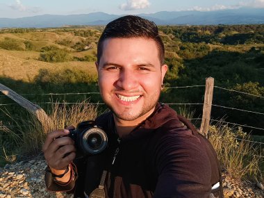Kolombiya 'nın Huila şehrinde, Villavieja kırsalındaki bir tepede kamerasını tutarken gülümseyen sakallı bir Kolombiyalının selfie' si. Dijital göçebelik, özgürlük ve seyahat kavramı