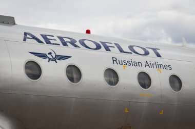 Riga, Latvia - June 1, 2023: Aeroflot Russian Airlines logo and title on the fuselage of an passenger airplane in a bad shape with dark clouds clipart