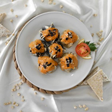 Japon Mentai soslu Dimsum. Beyaz tabakta servis edilmiş. Tempeh, tavuk ve siyah mürekkepbalığından yapılmış degiştirilmiş gamsum. Kapat ve seçici odak resmi.