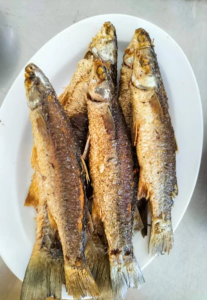 stock image Portion of fried small Black Sea red mullet fishes in plate on gray table. Fresh fried little red mediterranean fish. Selective focus.