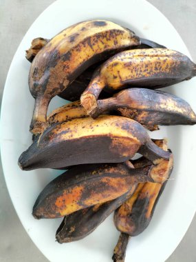 Kaynamış birkaç Saba muzu beyaz tabağa konur. Asyalılar kahvaltıda sıcak içeceklerle haşlanmış muz yemeyi severler..