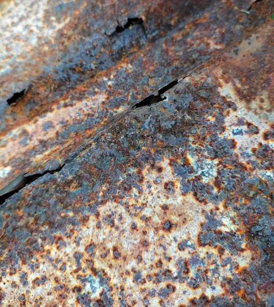 Close up. Brown, black and yellow rust on white enamel. Rusted brown and white abstract texture. Corroded white metal background. Rusty metal surface with streaks of rust.