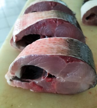 Süt balığı, alabalık, biftek, kesme tahtasında bir dilim taze çiğ balık. Seçici odak.