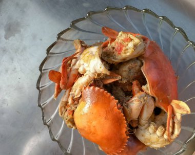 Sıcak sarımsak soslu yengeç. Beyaz arka planda beyaz cam tabakta baharatlı soslu haşlanmış yengeç. Asya yemekleri. Seçici odak.