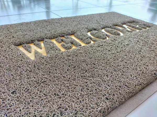 Selective focus. The doormat is made of synthetic material with the word welcome screen printed.