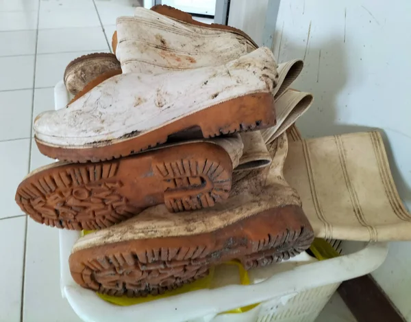 Seçici odaklanma. Terk edilmiş ahırda bırakılmış eski lastik botlar. Çizmeler yığınla var. Kirli çizmeler..