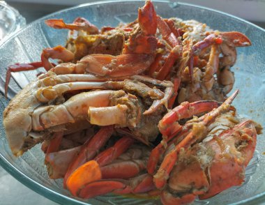 Sıcak sarımsak soslu yengeç. Beyaz arka planda beyaz cam tabakta baharatlı soslu haşlanmış yengeç. Asya yemekleri. Seçici odak.