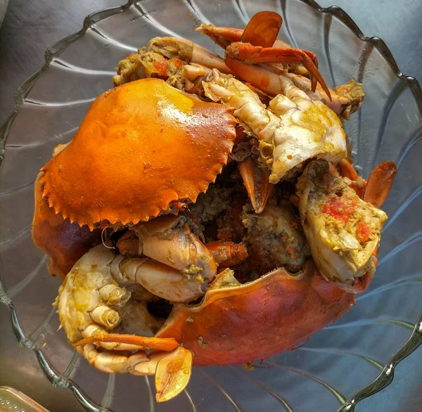 Sıcak sarımsak soslu yengeç. Beyaz arka planda beyaz cam tabakta baharatlı soslu haşlanmış yengeç. Asya yemekleri. Seçici odak.