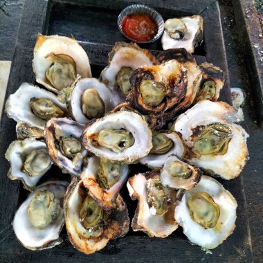 Servis tabağında istiridye, baharatlı deniz ürünleri soslu orta pişmiş istiridye, acılı tabak, acı biber ve soya sosu. Endonezya yemekleri popüler deniz ürünleri menüsü. 