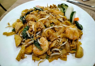 Seçici odaklanma. Kızarmış pirinç eriştesi ya da Endonezya 'da kahvaltı ya da başka bir yemek olarak meşhur olan char kway teow. Çin mutfağı. Kızarmış deniz ürünleri..