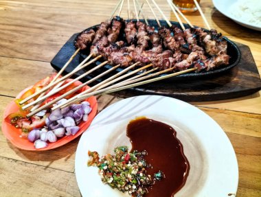 Yakın plan. Elektrikli ocakta kambing ya da keçi satay. Yeşil biberli soya sosu, domates ve soğan dilimleri ile servis edilir.. 