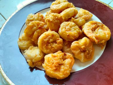 Un Kızarmış Karides un ve yumurtalarla karıştırılıp sıcak yağda kızartılmış bir karides tabağıdır. Kırmızı tabakta servis edilmiş. Seçici odak.