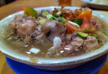 Dilimlenmiş domates, soğan ve kızarmış soğanla servis edilen yahni kuzu çorbasının yakın görüntüsü. Endonezya yemeği. Lezzetli yemek..