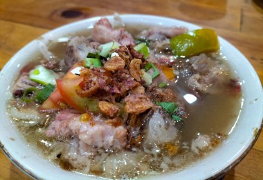 Dilimlenmiş domates, soğan ve kızarmış soğanla servis edilen yahni kuzu çorbasının yakın görüntüsü. Endonezya yemeği. Lezzetli yemek..