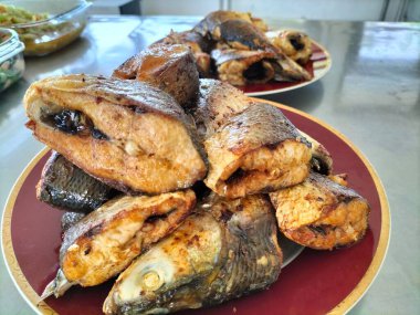 Kızarmış Süt Balığı, Endonezya ev yemeği olarak zerdeçal baharatıyla kızartılmış. Tabakta servis edilmiş. Seçici odak