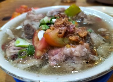 Yakın plan. Sop Kambing veya Soup Goat, Endonezya 'nın geleneksel bir yemeği olan dilimlenmiş domates, soğan ve soğan ile servis edilen genç keçi etinden yapılan bir yemektir..