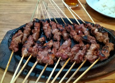 Yakın plan. Elektrikli ocakta kambing ya da keçi satay. Yeşil biberli soya sosu, domates ve soğan dilimleri ile servis edilir.. 