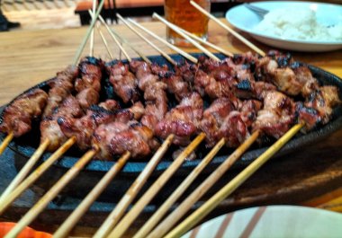 Yakın plan. Elektrikli ocakta kambing ya da keçi satay. Yeşil biberli soya sosu, domates ve soğan dilimleri ile servis edilir.. 