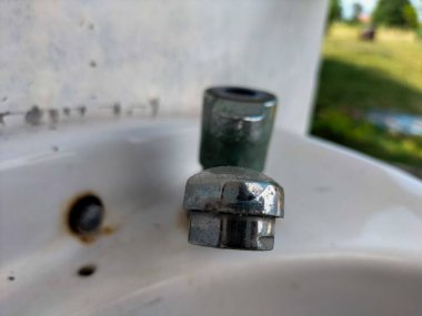 Selective focus. Old rusty sink faucet in toilet. Rust streaks, calcium scale, hard water. Concept of poor water quality. clipart