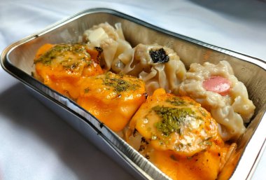 Lezzetli Dim Sum 'un fotoğrafı. Çeşitli soslu Dimsum, sosis, nori, peynir parçaları ve mentai sosu. Alüminyum bir kutuda servis edilmiş..