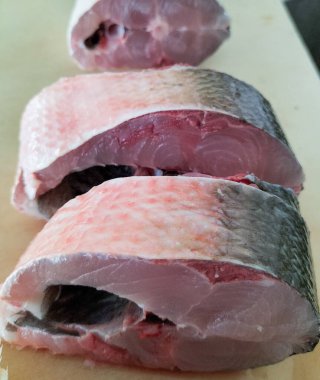 Süt balığı, alabalık, biftek, kesme tahtasında bir dilim taze çiğ balık. Seçici odak.