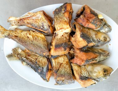 Kızarmış Süt Balığı, Endonezya ev yemeği olarak zerdeçal baharatıyla kızartılmış. Tabakta servis edilmiş. Seçici odak.