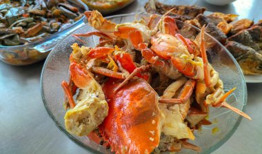 Sıcak sarımsak soslu yengeç. Beyaz arka planda beyaz cam tabakta baharatlı soslu haşlanmış yengeç. Asya yemekleri. Seçici odak.