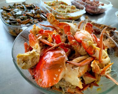 Sıcak sarımsak soslu yengeç. Beyaz arka planda beyaz cam tabakta baharatlı soslu haşlanmış yengeç. Asya yemekleri. Seçici odak.