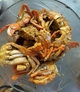 Sıcak sarımsak soslu yengeç. Beyaz arka planda beyaz cam tabakta baharatlı soslu haşlanmış yengeç. Asya yemekleri. Seçici odak.