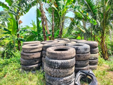 Üst üste dizilmiş eski lastiklerin görüntüsü uzun sıralarda kesişiyor. Geri dönüşüm için eski lastik ve lastiklerle dolu. Atık lastik lastiklerin yeniden kullanılması. 