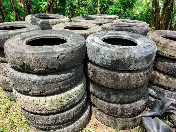 Üst üste dizilmiş eski lastiklerin görüntüsü uzun sıralarda kesişiyor. Geri dönüşüm için eski lastik ve lastiklerle dolu. Atık lastik lastiklerin yeniden kullanılması. 