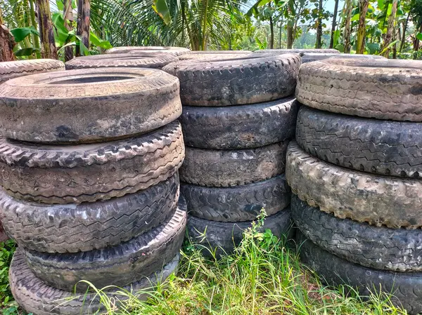 Üst üste dizilmiş eski lastiklerin görüntüsü uzun sıralarda kesişiyor. Geri dönüşüm için eski lastik ve lastiklerle dolu. Atık lastik lastiklerin yeniden kullanılması. 