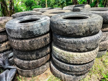 Seçici odaklanma. Boş arazide bırakılan kullanılmış lastik yığınları çevre için israfa dönüşüyor. Endonezya 'da eski lastik araba lastikleri.