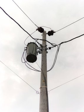 Seçici odaklanma. Kablolar ve diğer bağlantı ekipmanlarıyla bir elektrik direği Endonezya 'da açık bir gökyüzüne karşı duruyor.